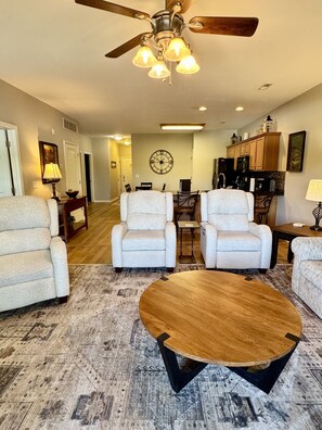 A living room with a ceiling fan, a wooden coffee table, and two armchairs. - Lower Level Vacation Condo  B-3 at Vickery Resort by RedAwning (Hollister)