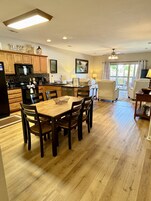 Una cocina moderna con armarios de madera, una mesa de comedor con sillas, un refrigerador y un microondas.