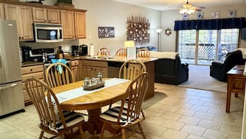 A modern kitchen with wooden cabinets, a central island, and a dining area with a table and chairs.