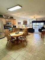 Una cocina moderna con armarios de madera, una isla central y un comedor con mesa y sillas.