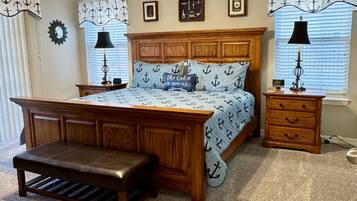 A bedroom with a wooden bed, a desk, a bench, a ceiling fan, and two bedside lamps.