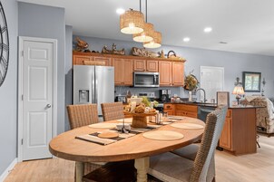 Una cocina moderna con comedor, que cuenta con una isla central, armarios de madera y un microondas empotrado.
