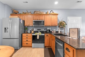 A modern kitchen with wooden cabinets, stainless steel appliances, and a granite countertop.