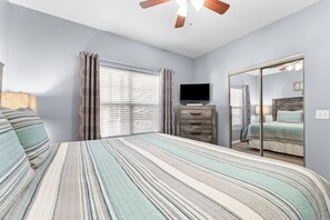 A bedroom with a bed, a dresser, a television, and a mirror.
