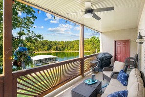 Un espace extérieur abrité avec vue sur un lac, un barbecue et du mobilier d’extérieur.