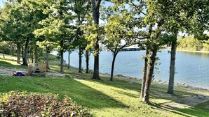 A lakeside park with a children's play area, benches, and a clear view of the water.