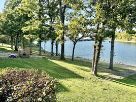 Un parque junto al lago con zona de juegos infantiles, bancos y vista despejada del agua.