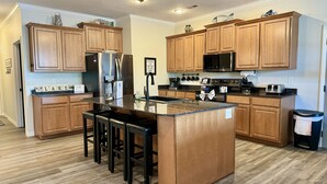 A modern kitchen with wooden cabinets, stainless steel appliances, and a central island with bar stools.