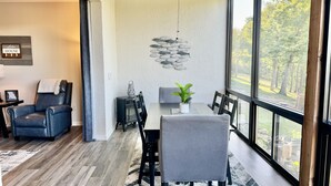 A modern dining area with a table, chairs, a potted plant, and a wall art piece.