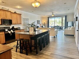 Una cocina moderna con armarios de madera, una isla central con taburetes, un microondas y una estufa.