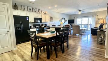 A spacious kitchen with a dining area, wooden flooring, and a ceiling fan.