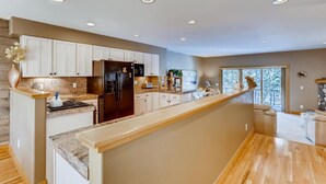 Une cuisine moderne avec des armoires blanches, un réfrigérateur en acier inoxydable et un îlot central en bois.