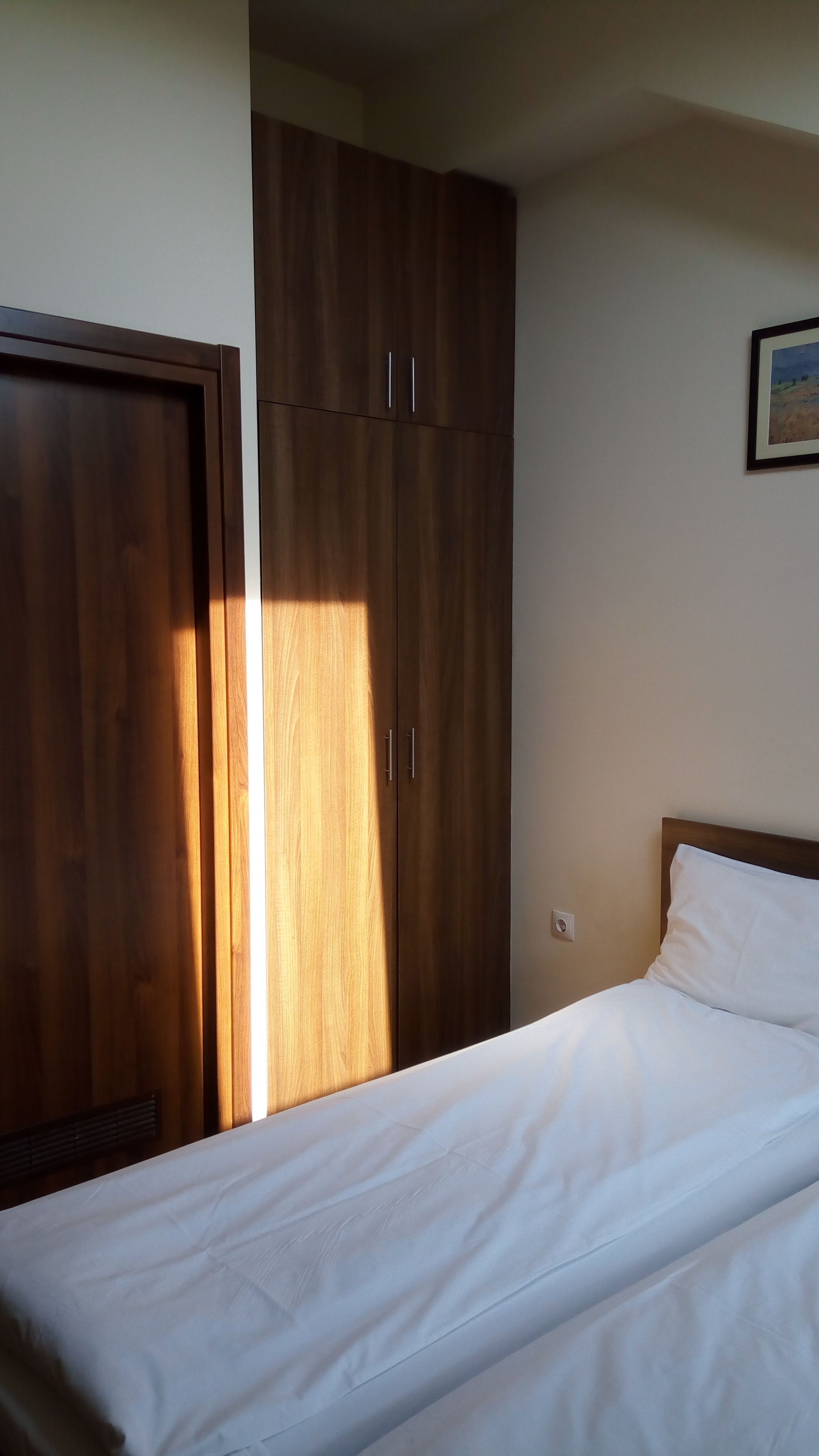 Un dormitorio con cama, armario de madera y un cuadro en la pared.
