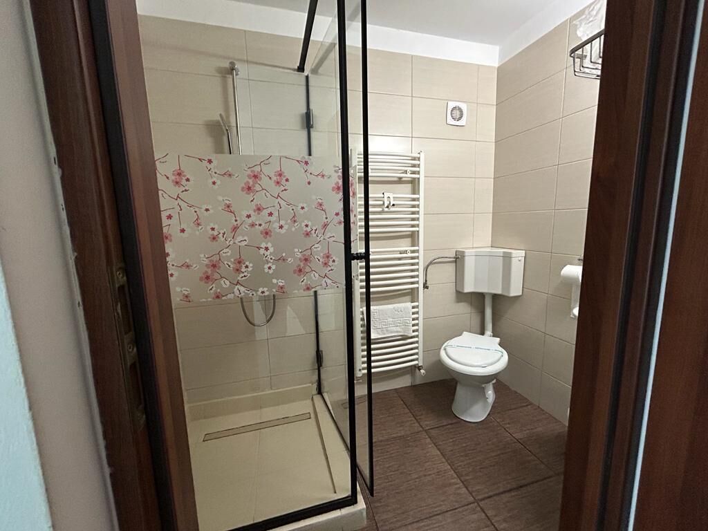 Un baño con cabina de ducha de vidrio, inodoro y perchero para toallas.
