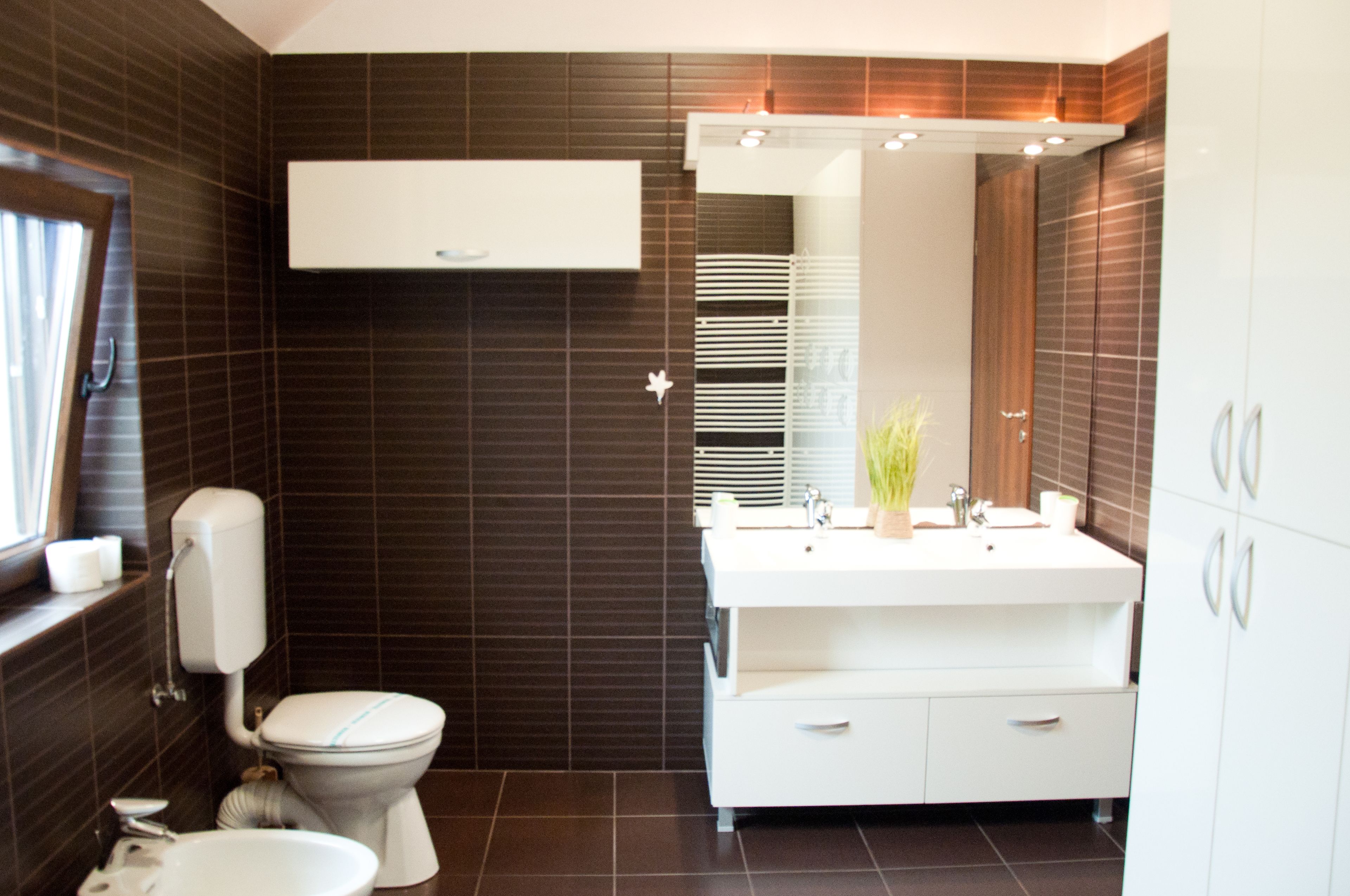 A modern bathroom with a toilet, sink, and cabinet.