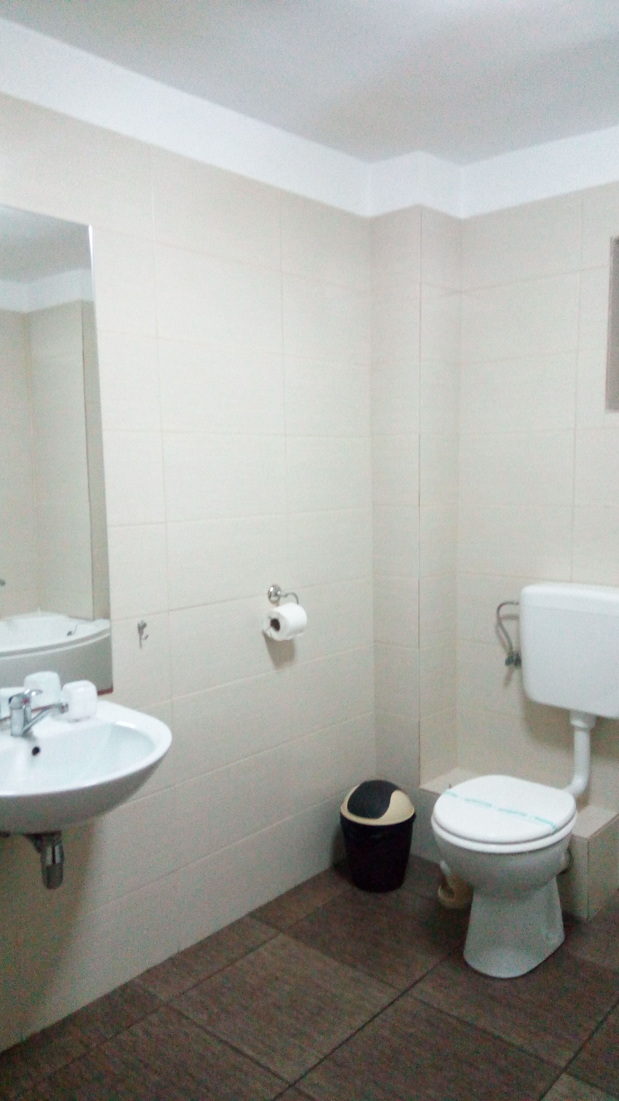 Un baño con lavamanos, inodoro y espejo blancos.