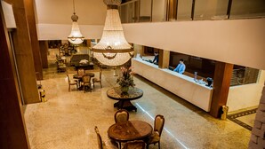 A lobby with a round table and chairs, a reception desk, and a chandelier. - Garbos Trade Hotel (Mossoro)