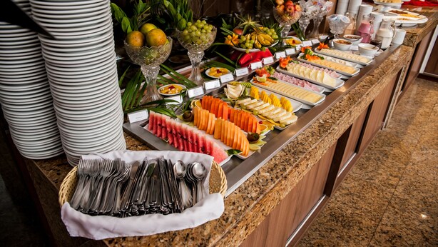 A buffet with various food items and utensils. - Garbos Trade Hotel (Mossoro)
