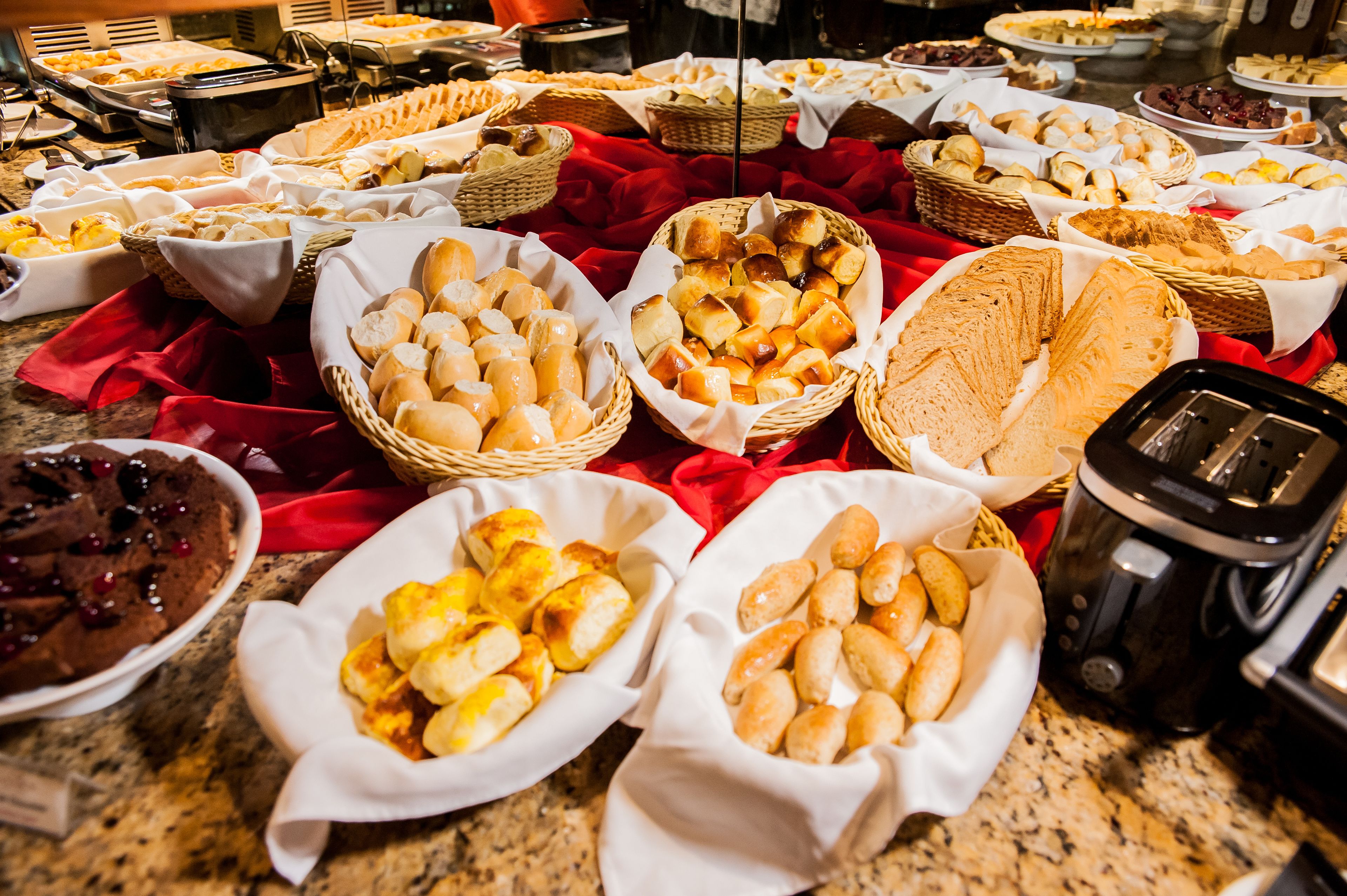 Un bufé con diversos panes y pasteles expuestos en cestas.