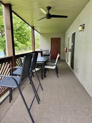 A covered patio area with a ceiling fan, a table with chairs, a door, and a fire extinguisher.