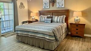A bedroom with a bed, two bedside tables with lamps, a ceiling fan, and artwork on the wall. - Lakefront Condo A-2 at Vickery Resort by RedAwning (Hollister)
