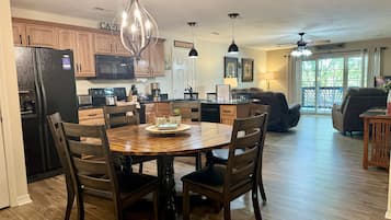 A spacious kitchen with wooden cabinets, a dining table with chairs, and a living area with a couch and a TV.