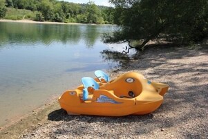 Una pequeña lancha inflable sobre una orilla de grava cerca de un lago.