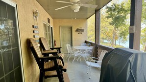 A covered patio area with outdoor seating, including wooden chairs and a table, and a ceiling fan. - Lakefront Condo A-2 at Vickery Resort by RedAwning (Hollister)