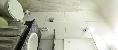 A modern bathroom with a marble backsplash, a white sink, a towel rack, and a toilet.