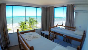Una habitación con dos literas, una mesita pequeña y ventana vista al mar.
