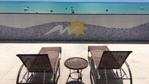 A beachside view with lounge chairs and a sun motif on the wall. - Maraga Beach Hostel (Maragogi)