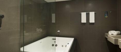 Un baño moderno con ducha de vidrio, una bañera grande y un lavamanos.