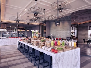 Een moderne bar met een marmeren aanrecht, meerdere barkrukken en een ruime keuze aan eten en drinken.