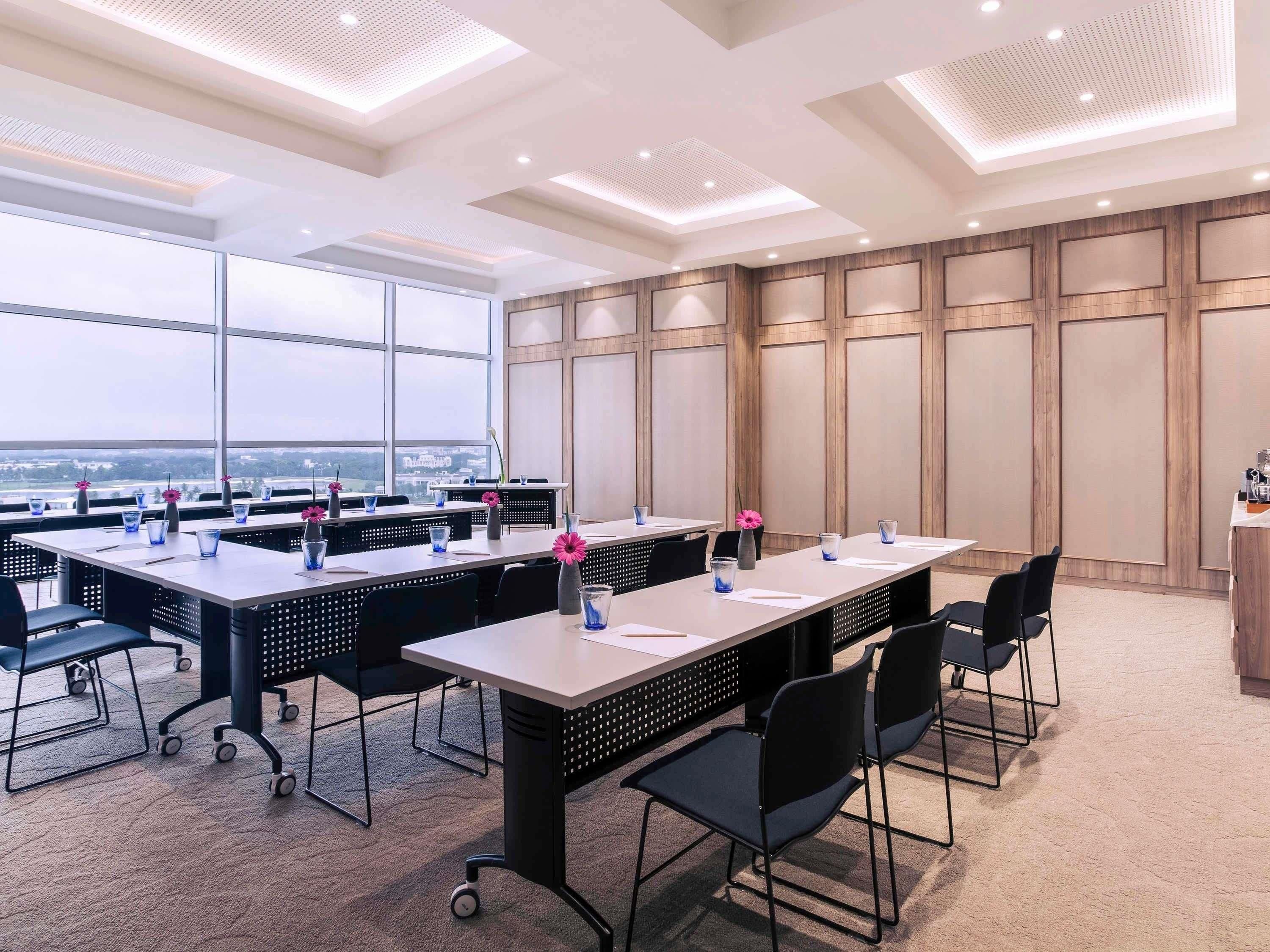 A conference room with tables, chairs, and a large window offering a view.