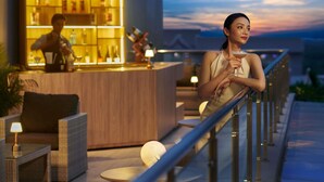 Een moderne bar met een bartender, een goed verlichte toonbank en uitzicht op de zonsondergang.