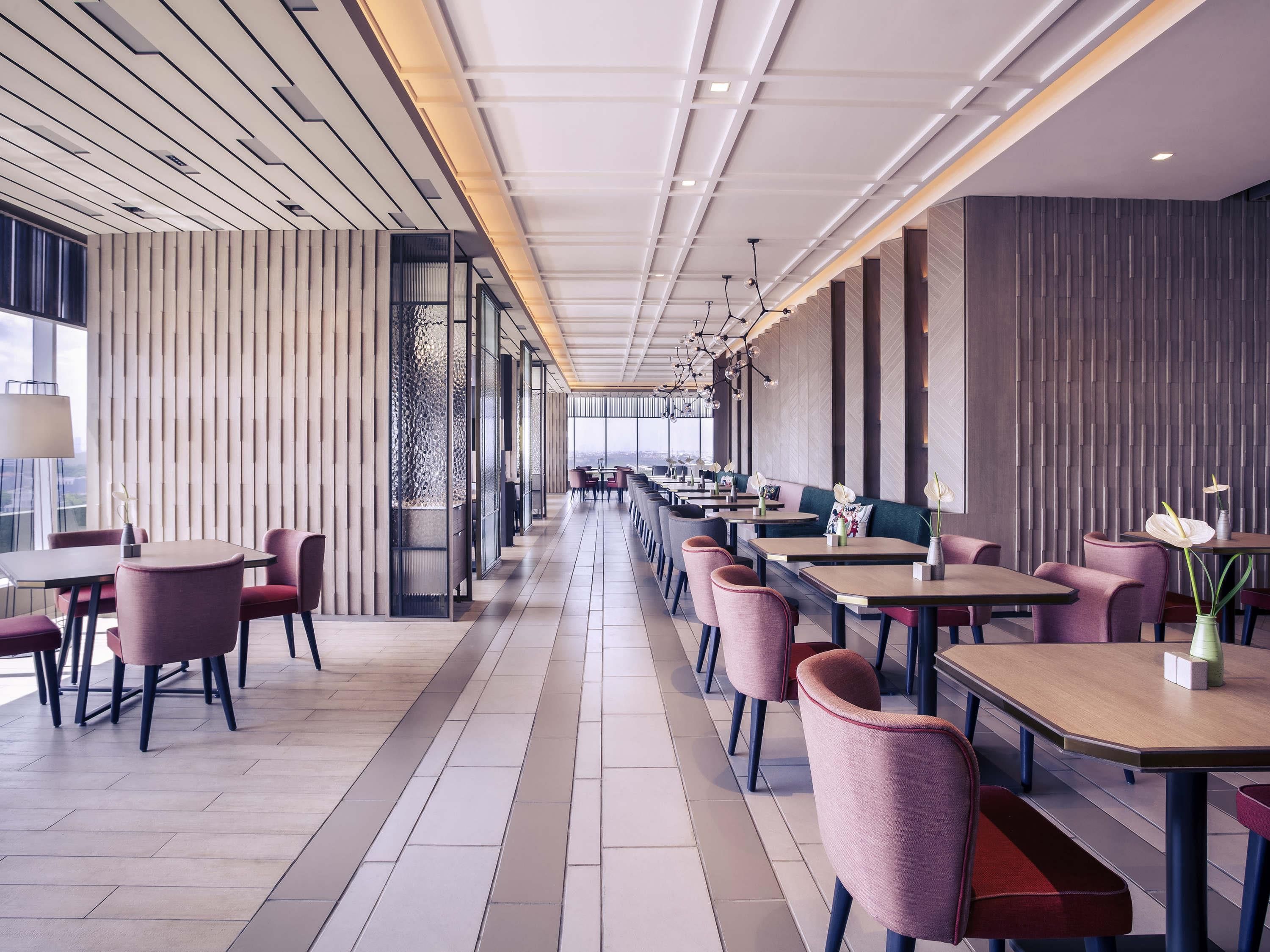 Un restaurante moderno con una barra larga, varias mesas y sillas.