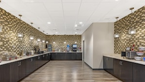 A modern kitchen with a checkered tile backsplash, wooden flooring, and stainless steel appliances. - Best Western Plus Centralia Hotel & Suites (Centralia)