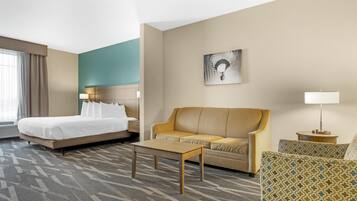 A hotel room with a bed, a sofa, a coffee table, and a small table with a lamp.