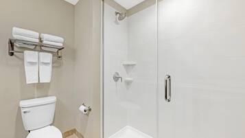 Une salle de bain moderne équipée de toilettes, d’une douche à parois de verre et d’un porte-serviettes avec des serviettes pliées.