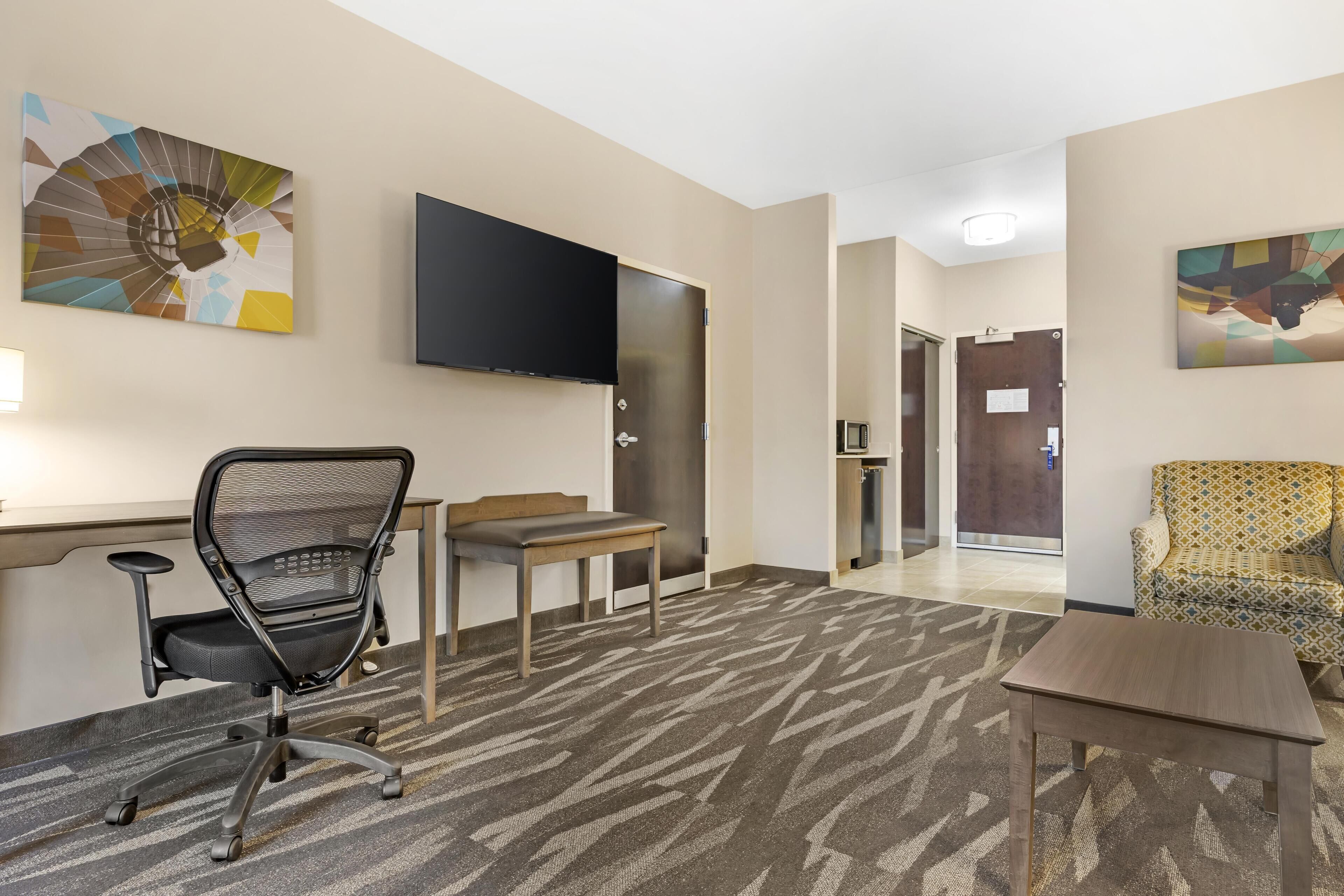 A hotel room with a desk, office chair, and a sofa.