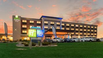 Ein Holiday Inn Express & Suites Hotel mit Parkplatz und Grünfläche davor.