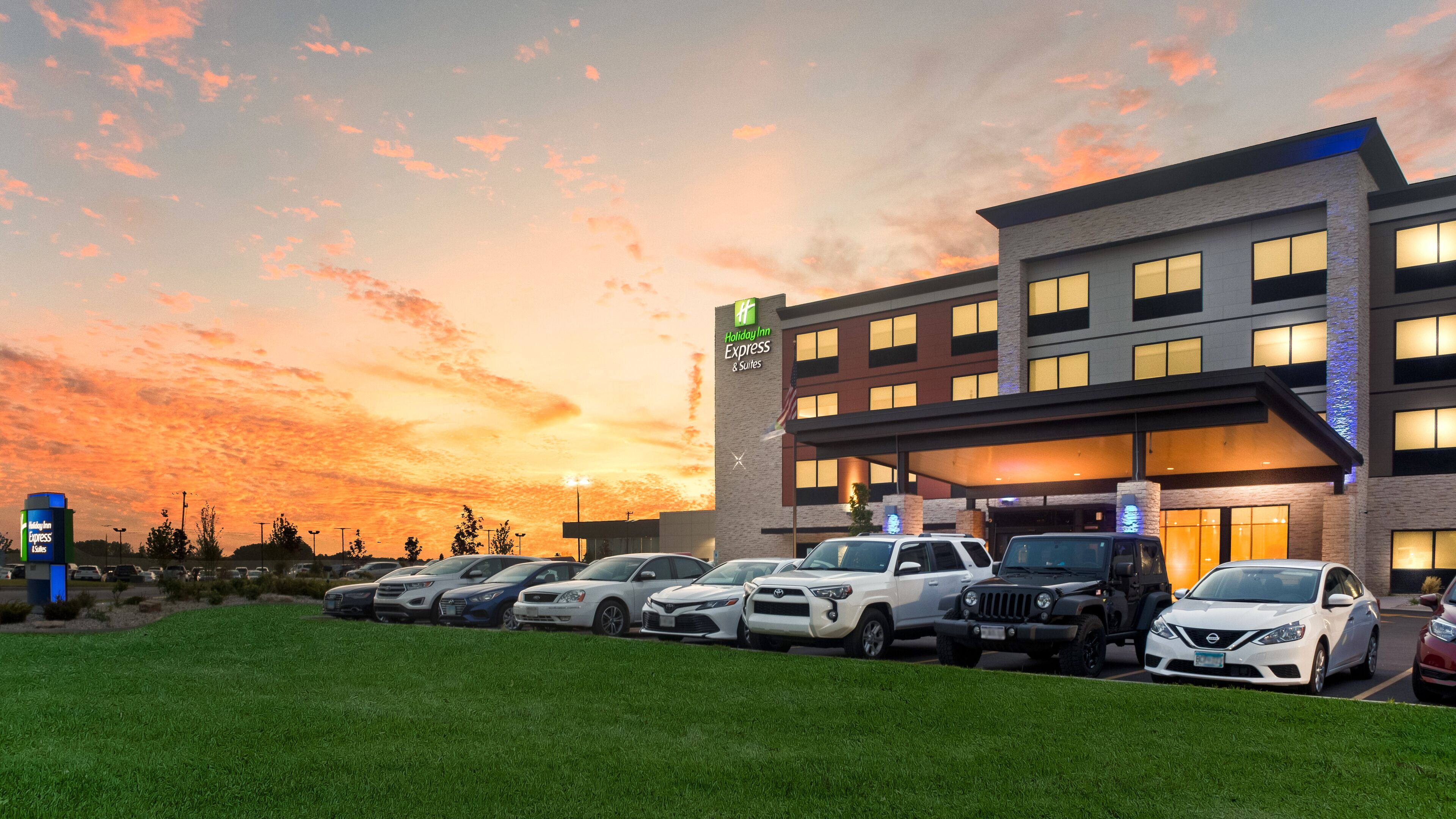 Un hôtel Holiday Inn Express & Suites doté d’un grand parking rempli de voitures.