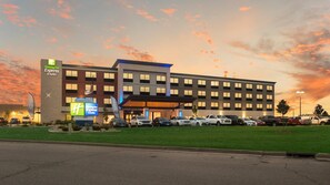 Ett Holiday Inn Express & Suites-hotell med en parkeringsplats och en gräsyta framför.