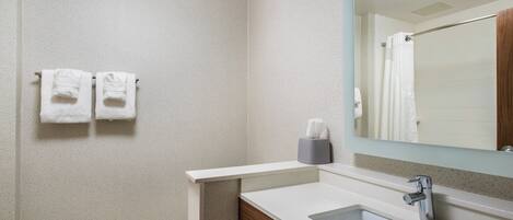 A bathroom with a toilet, sink, mirror, and two towels hanging on the wall.