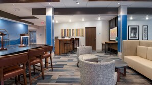 A hotel lobby with a bar area, seating, and a wall with colorful artwork. - Holiday Inn Express & Suites Racine by IHG (Mount Pleasant)