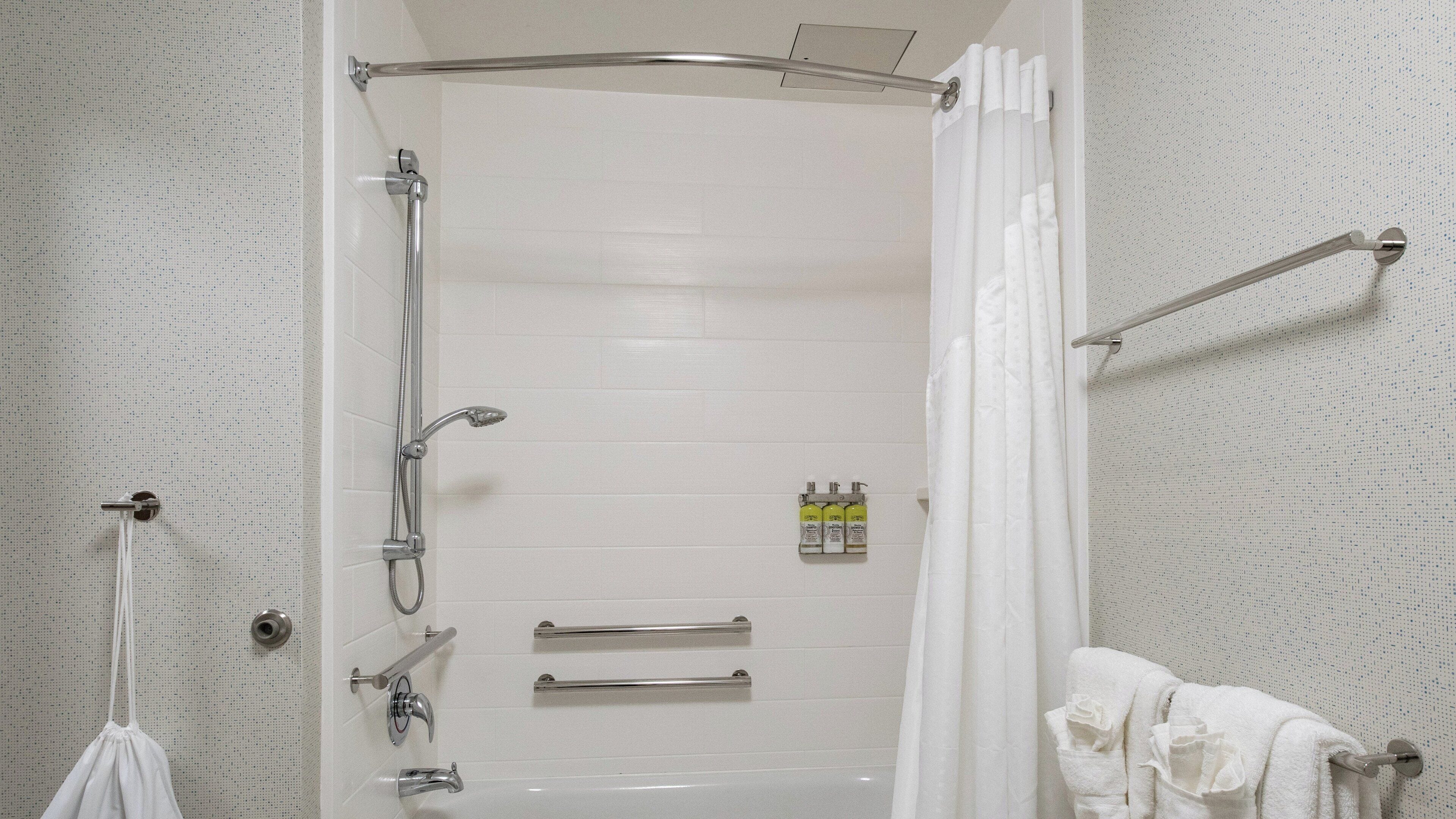 Un baño con ducha, inodoro y barra para toallas.