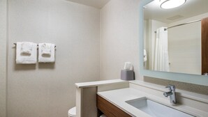 A bathroom with a white sink, a mirror, and two towels hanging on the wall.