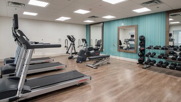 A gym with treadmills, exercise bikes, and a rack of dumbbells.