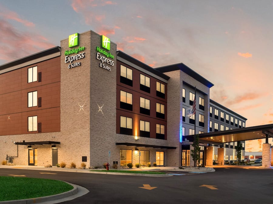 A Holiday Inn Express & Suites building with a brick facade, multiple windows, and a covered entrance.