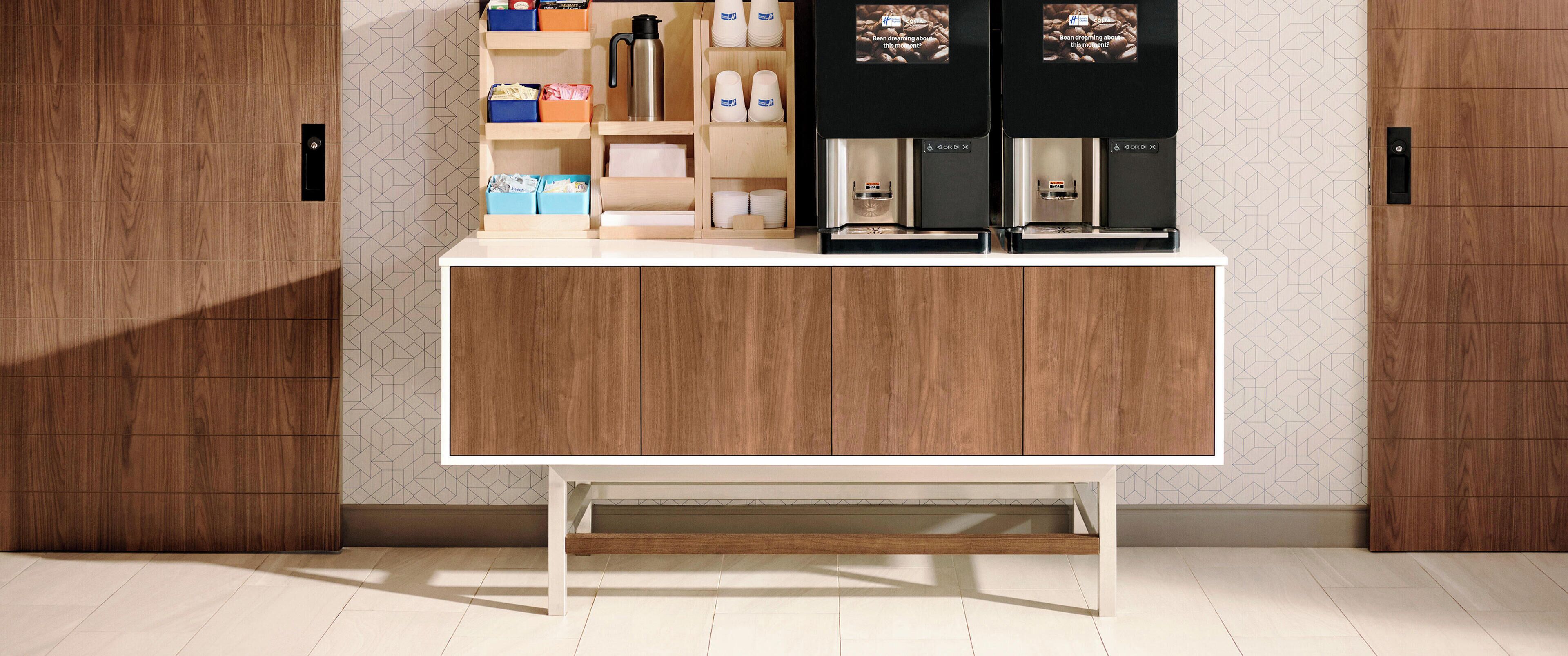A modern kitchen with wooden cabinets, a white countertop, and a built-in coffee machine.
